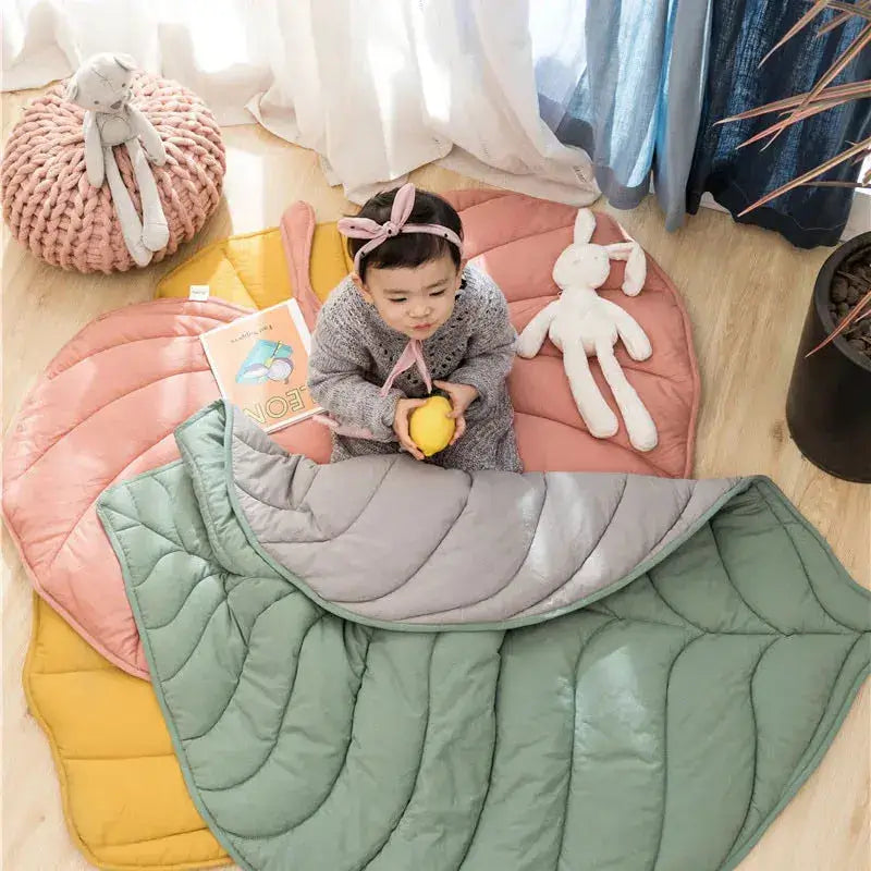 Une petite fille assise sur un tapis d'éveil - Monde à maman